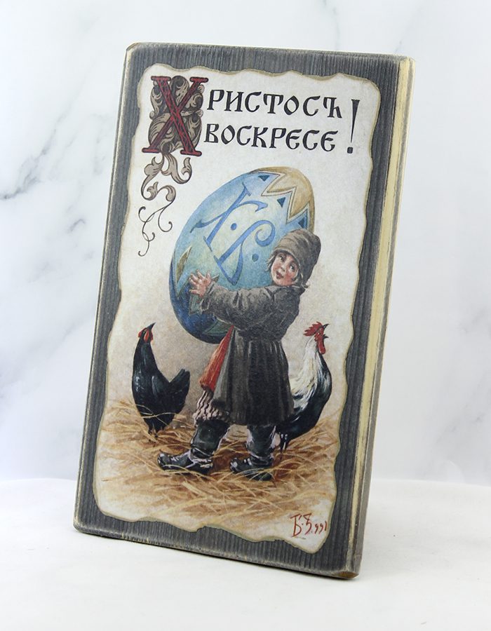 Крестьянский мальчик держит гигантское голубое яйцо с надписью ХВ, рядом две чёрные курочки, надпись «Христос воскрес» – старинная открытка на доске
